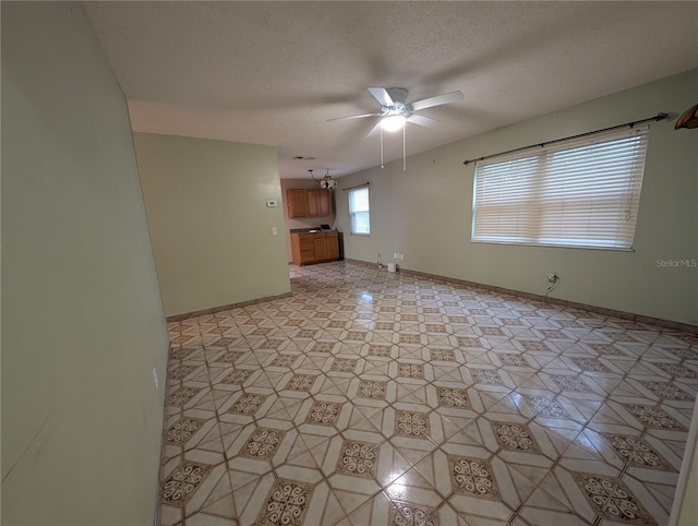 spare room with ceiling fan, baseboards, and a textured ceiling