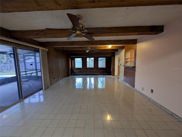 unfurnished room with ceiling fan, wooden walls, baseboards, and beamed ceiling