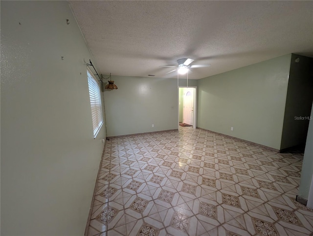 empty room with ceiling fan, a textured ceiling, and baseboards