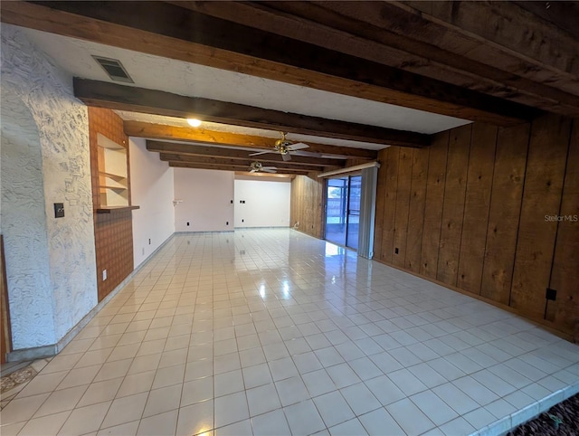 interior space featuring beam ceiling, light tile patterned floors, visible vents, ceiling fan, and wooden walls