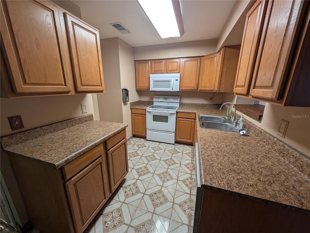 kitchen with brown cabinetry, white appliances, visible vents, and a sink