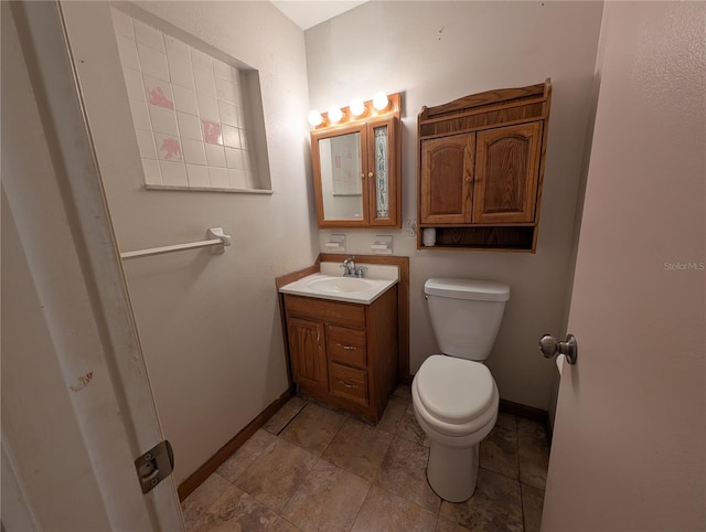 bathroom featuring toilet, baseboards, and vanity