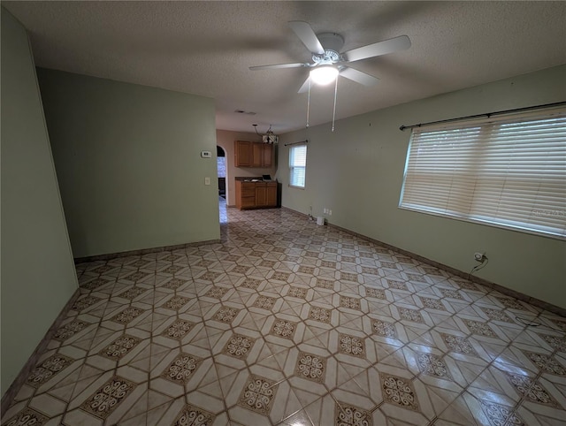 spare room featuring a textured ceiling, ceiling fan, and baseboards