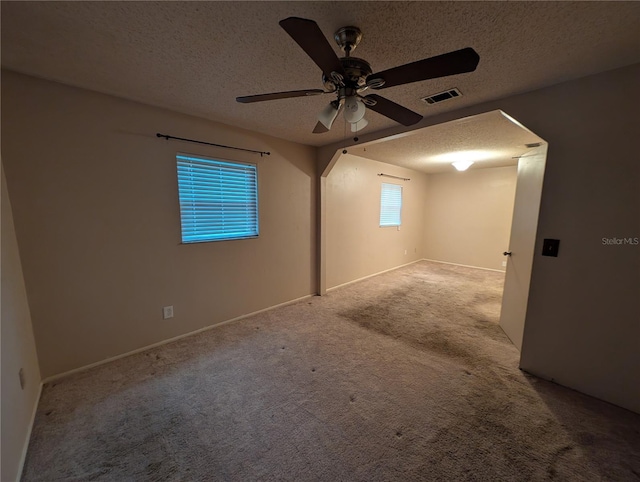 unfurnished room with ceiling fan, visible vents, a textured ceiling, and light colored carpet