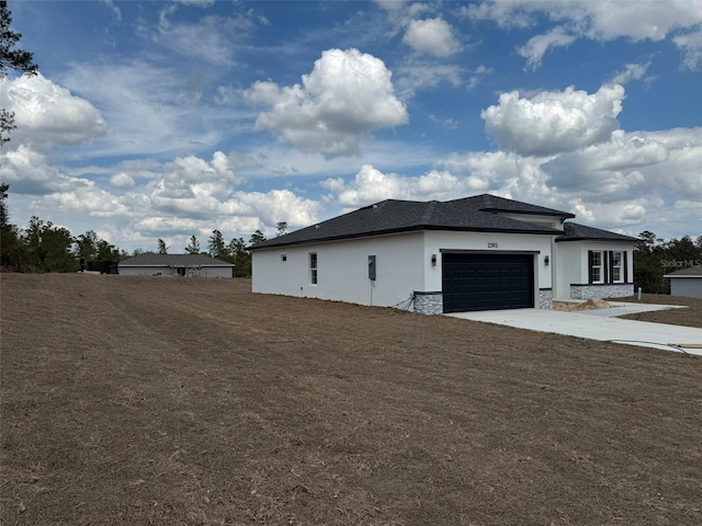 view of side of home with a garage, stone siding, concrete driveway, and stucco siding