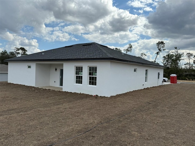 view of side of property with roof with shingles and stucco siding