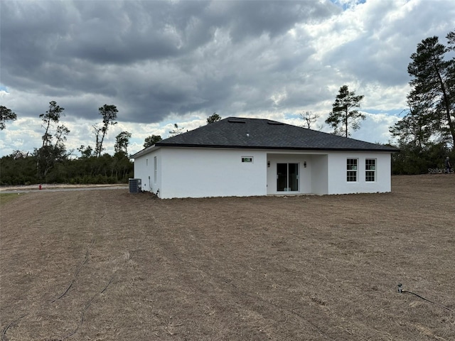 rear view of property featuring stucco siding and central AC unit