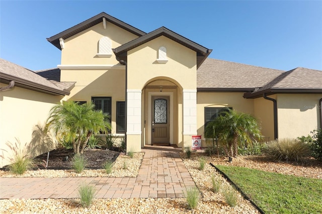 view of front of home featuring roof with shingles and stucco siding