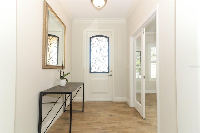 entrance foyer with ornamental molding, light wood-style flooring, and baseboards