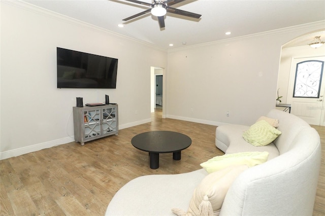 living area with baseboards, arched walkways, ceiling fan, ornamental molding, and wood finished floors