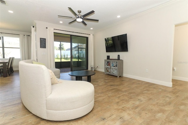 living area featuring light wood finished floors, plenty of natural light, and crown molding