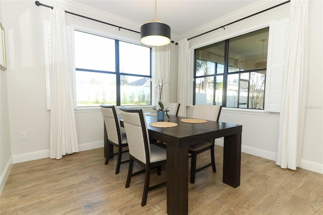 dining space featuring baseboards, light wood finished floors, and crown molding