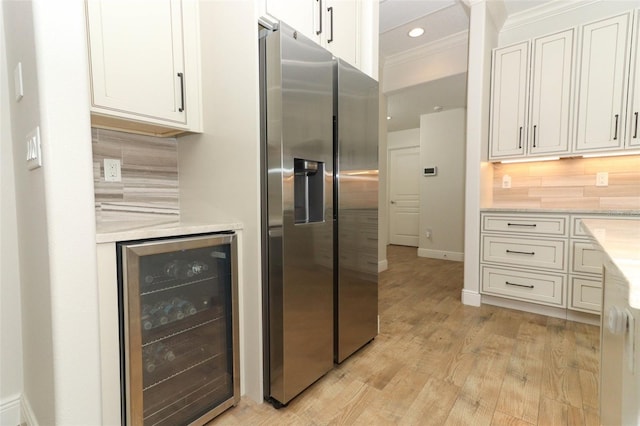 kitchen featuring beverage cooler, light countertops, backsplash, and stainless steel fridge with ice dispenser