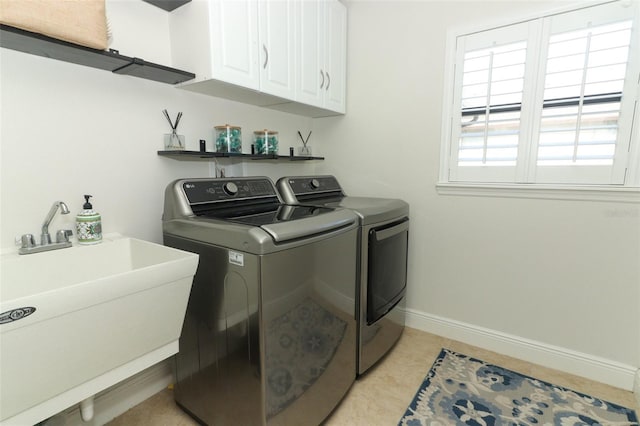 clothes washing area with baseboards, a sink, cabinet space, and washer and dryer