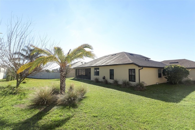 exterior space featuring fence, a lawn, and stucco siding