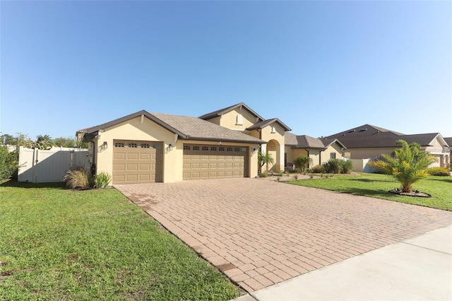 view of front of property with an attached garage, fence, decorative driveway, stucco siding, and a front yard