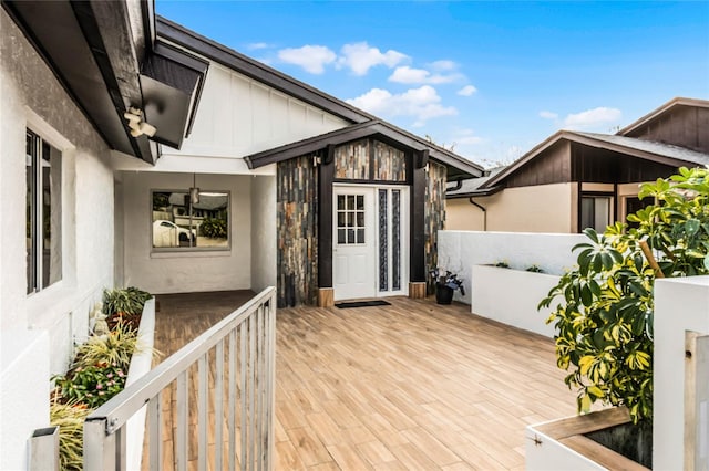 view of exterior entry featuring board and batten siding and a wooden deck