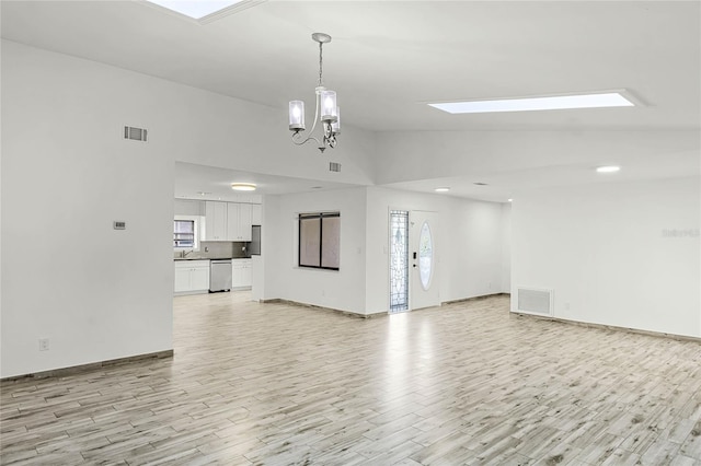 unfurnished living room with light wood-style flooring, lofted ceiling with skylight, and visible vents