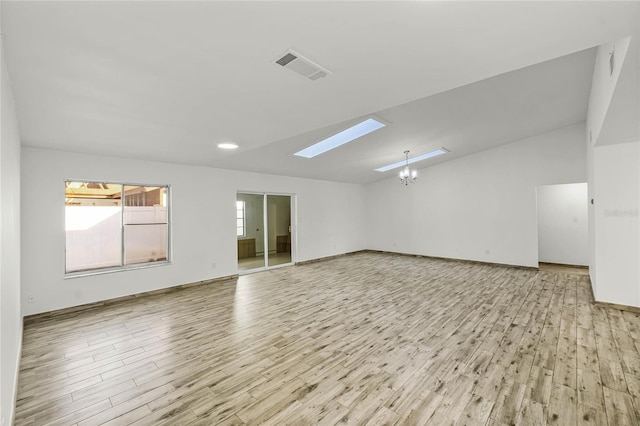 unfurnished room featuring lofted ceiling with skylight, visible vents, light wood-style floors, and an inviting chandelier