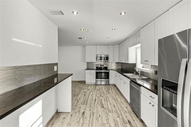 kitchen featuring light wood-style flooring, stainless steel appliances, a sink, visible vents, and white cabinets