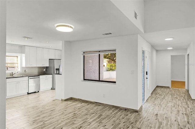 kitchen featuring appliances with stainless steel finishes, dark countertops, white cabinets, and a sink