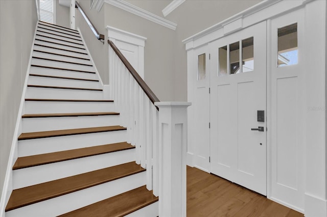 foyer entrance featuring ornamental molding, light wood-style flooring, and stairs