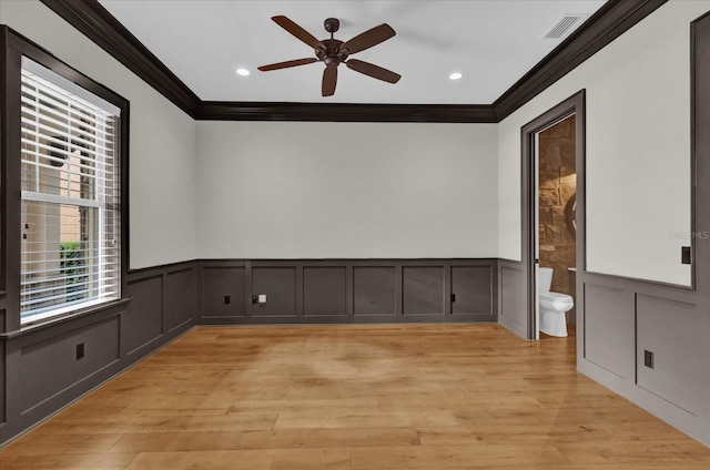 empty room with light wood finished floors, visible vents, a ceiling fan, and ornamental molding