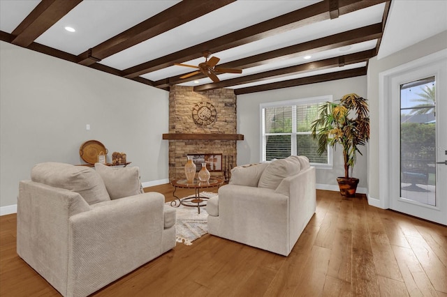 living room featuring a ceiling fan, a fireplace, baseboards, and hardwood / wood-style floors