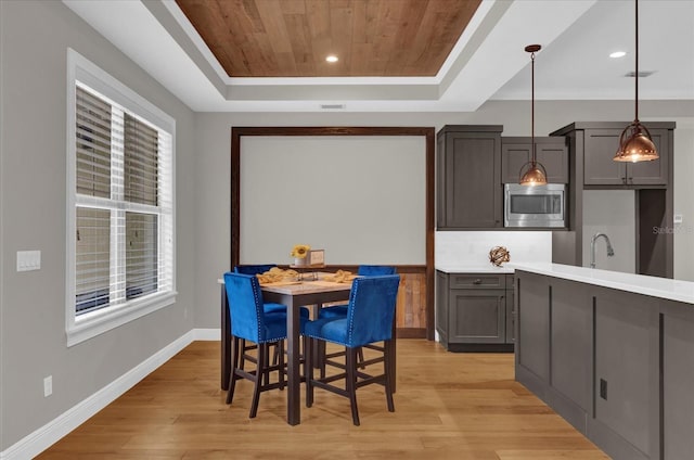 dining area with wooden ceiling, light wood finished floors, baseboards, and a raised ceiling