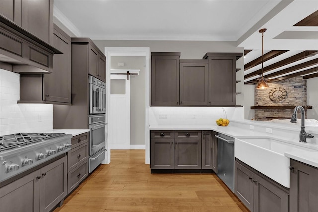 kitchen with stainless steel appliances, pendant lighting, light countertops, and a barn door