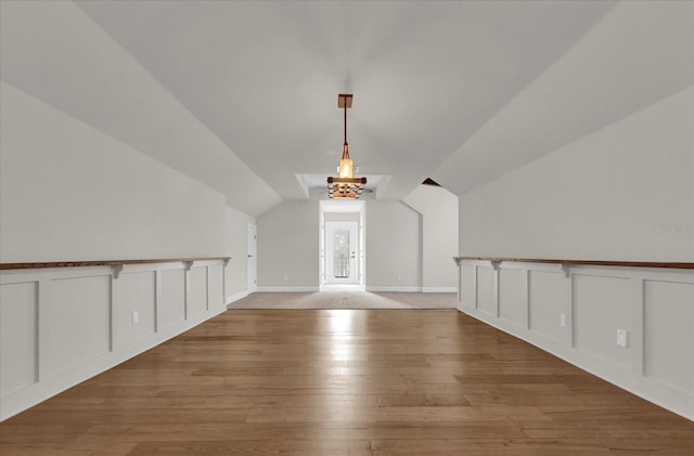 bonus room featuring vaulted ceiling, wood finished floors, and a decorative wall