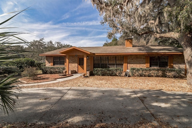 view of front of home with a chimney and brick siding