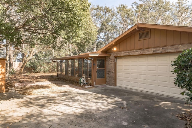 view of home's exterior with driveway, brick siding, and a sunroom