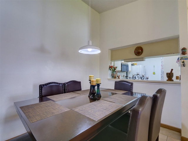 dining space featuring a towering ceiling, tile patterned flooring, and baseboards