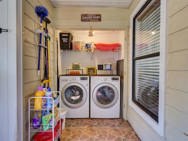 washroom with laundry area, washing machine and dryer, and stone finish flooring