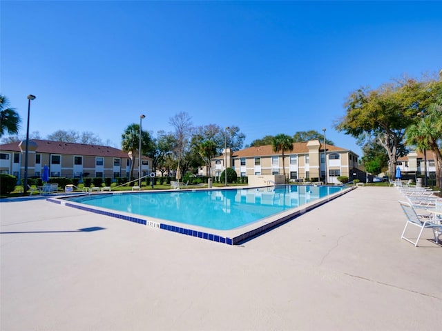 community pool with a residential view, a patio, and fence