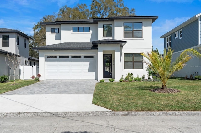 view of front of property with a garage, fence, decorative driveway, a front lawn, and stucco siding