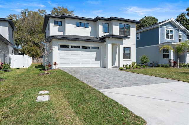 view of front of home with a garage, fence, decorative driveway, stucco siding, and a front yard