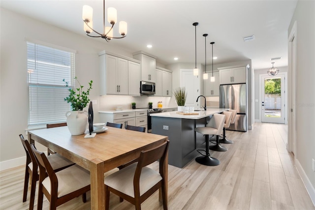 dining room with a notable chandelier, recessed lighting, visible vents, light wood-type flooring, and baseboards