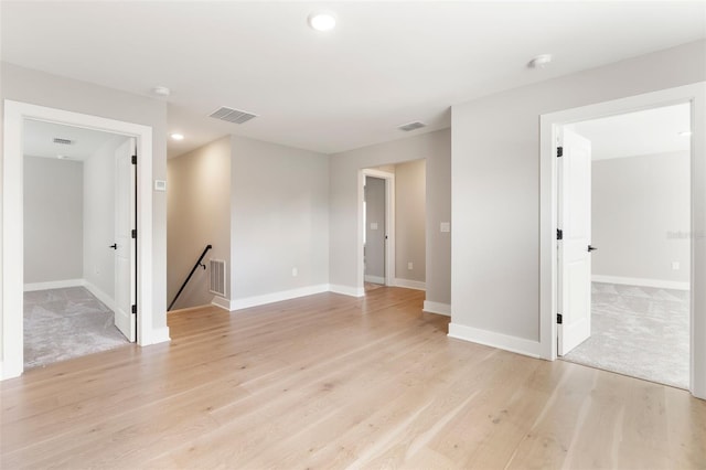 spare room featuring light wood finished floors, baseboards, and visible vents