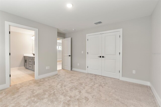 unfurnished bedroom with carpet floors, a closet, visible vents, ensuite bathroom, and baseboards