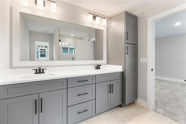 bathroom with visible vents, a sink, baseboards, and double vanity