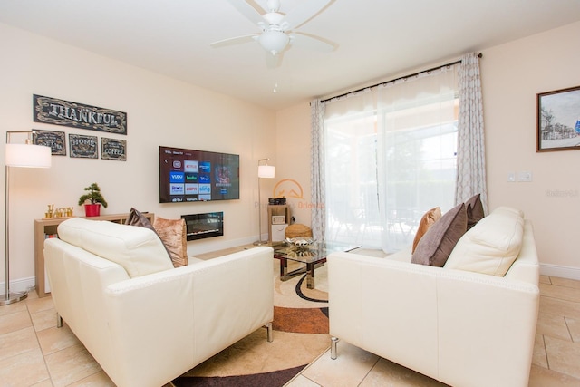 living area with ceiling fan, light tile patterned floors, a glass covered fireplace, and baseboards