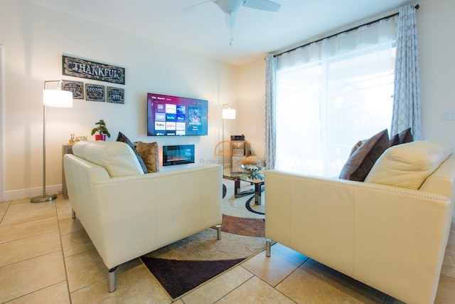 living room with light tile patterned floors, ceiling fan, and a glass covered fireplace