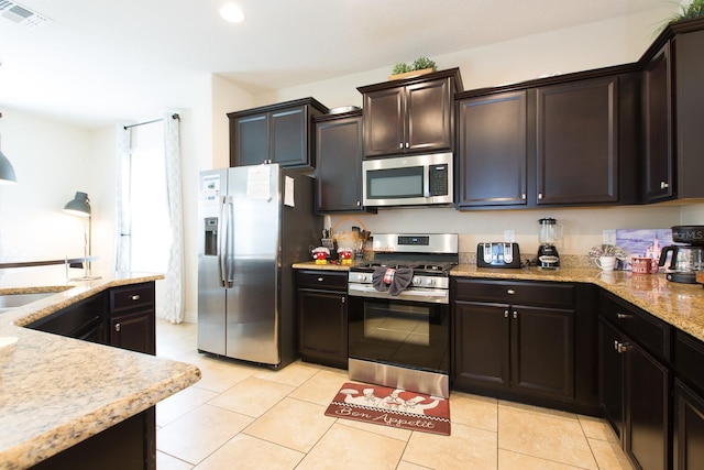 kitchen featuring stainless steel appliances, light stone countertops, visible vents, and light tile patterned floors