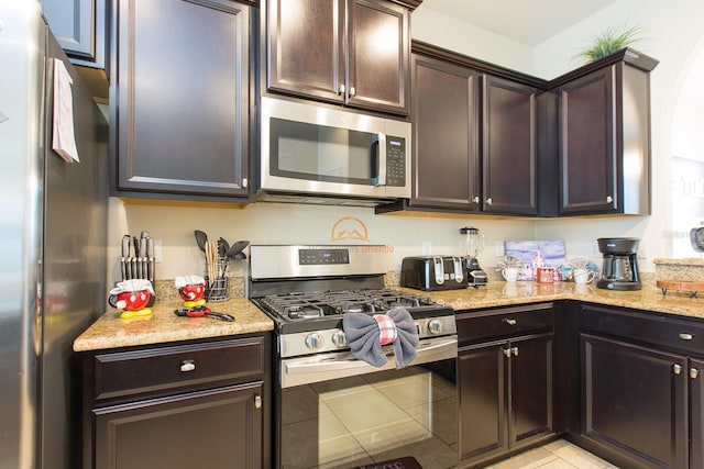 kitchen featuring appliances with stainless steel finishes, dark brown cabinetry, and light stone counters