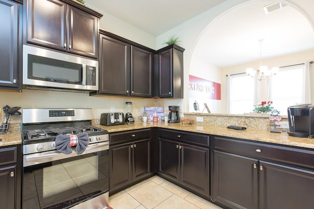 kitchen featuring stainless steel appliances, visible vents, hanging light fixtures, dark brown cabinets, and light stone countertops