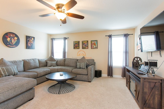 living area featuring ceiling fan, baseboards, and light colored carpet