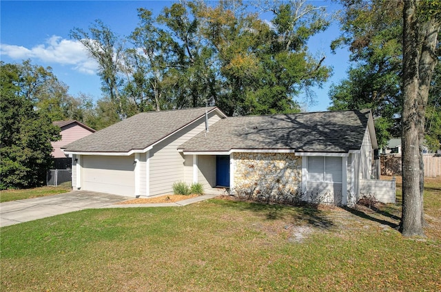 view of front of home featuring an attached garage, fence, concrete driveway, roof with shingles, and a front yard