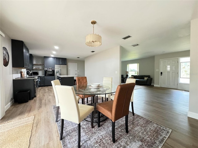 dining area with baseboards, visible vents, and light wood finished floors